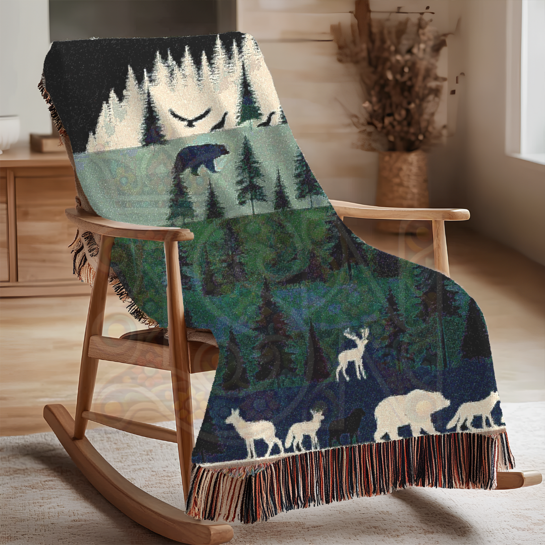 Wilderness-themed woven blanket draped on a rocker. Features layered forest scene with bears, deer, wolves, and birds in rich greens and blues—100% cotton, perfect for rustic or cabin decor.